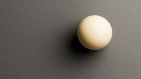 A minimalistic composition featuring a lone cream sphere resting on a smooth dark surface. The interplay of light and shadow creates a serene atmosphere, perfect for art projects or design inspiration.の素材