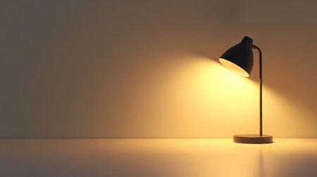 A minimalistic table lamp shines a warm light against a plain wall and surface, creating a cozy atmosphere for interior settings and home decor.の素材