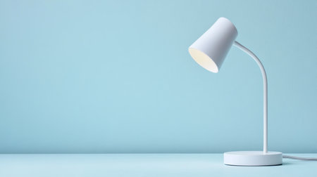 A sleek modern desk lamp stands elegantly on a soft blue background, ideal for creating a bright and stylish atmosphere in any workspace or home setting.の素材