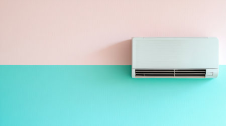 A sleek, modern air conditioning unit is mounted on a stylish wall divided into pastel pink and blue sections, creating a fresh and inviting atmosphere.の素材