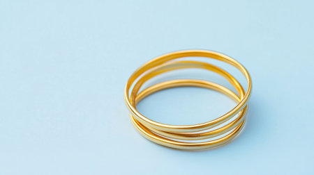 A captivating image of elegant gold rings set against a soft blue background, showcasing simple beauty and luxury, ideal for jewelry and fashion projects.の素材