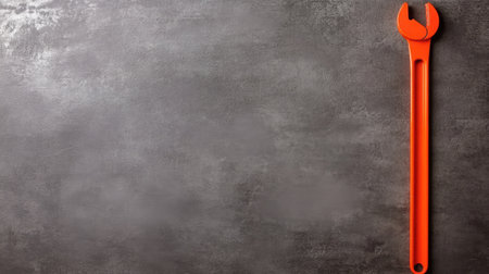 A vibrant orange adjustable wrench rests against a dark gray metallic backdrop, perfect for showcasing tools in DIY projects or home improvements.の素材