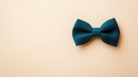 A classic teal bow tie rests elegantly on a soft beige background, making it an ideal choice for fashion photography and formal attire presentations.の素材