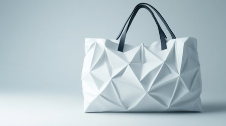 This image features a modern white tote bag with a unique geometric origami design and stylish black handles, perfect for showcasing contemporary fashion trends.の素材