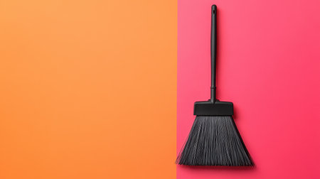A black dustpan sits against a striking orange and pink background, creating a vibrant and modern look for cleaning and organization themes.の素材