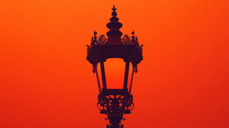 This captivating image showcases a vintage street lamp silhouette set against a stunning orange sunset sky. The intricate details of the lamp contrast beautifully with the warm tones of the evening light, creating a serene ambient atmosphere perfect for urban or decorative themes.の素材