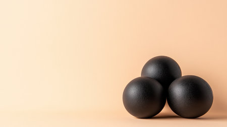 A striking arrangement of three black smooth balls positioned on a soft peach background, embodying minimalist design and modern aesthetic. Perfect for various creative projects.の素材