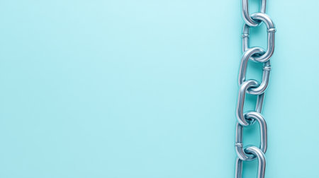 A close-up view of a metallic chain with links against a soft blue background showcasing the idea of strength, security, and minimalist design.の素材