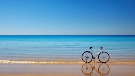 A tranquil beach scene featuring a bicycle resting on the soft sand with its reflection mirrored in the serene waters, surrounded by a clear blue sky.の素材