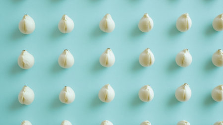 A captivating minimalist flat lay design featuring white garlic cloves arranged rhythmically on a soft blue background, emphasizing fresh ingredients for culinary inspiration.の素材