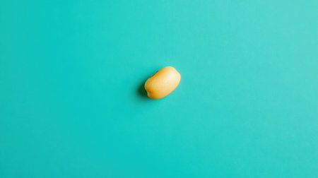 This image features a bright yellow banana placed against a vibrant turquoise background, creating an eye-catching contrast ideal for fresh and simple design projects.の素材