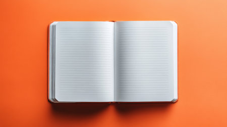 This image features a blank open notebook with lined pages set against a vibrant orange background, perfect for creative and educational projects.の素材