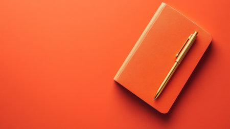 A vibrant orange notebook paired with a gold pen sits on a bold orange background, perfect for creative writing and organization. Ideal for inspiring ideas.の素材
