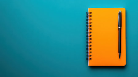 A bright orange notebook lies open beside a sleek black pen against a vibrant blue background, perfect for creative note-taking and organization.の素材