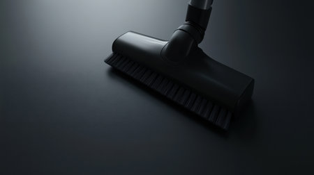 This image features a sleek black vacuum cleaner attachment resting on a dark surface, showcasing modern design and practicality for efficient cleaning solutions.の素材