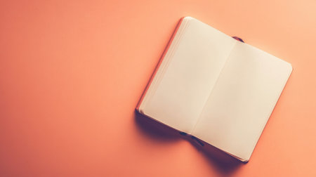 An open blank notebook lies on a smooth pastel orange surface, inviting creativity and inspiration for writing, planning, and organizing thoughts. Perfect for artistic projects or note-taking.の素材