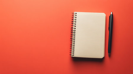 A blank notebook lies alongside a black pen on a vibrant orange background, ideal for creative projects, note-taking, or organizing thoughts.の素材
