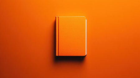 A vibrant orange notebook rests on a matching bright orange background, perfect for creative writing and note-taking. Ideal for minimalistic designs.の素材