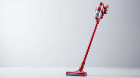 This image features a sleek red cordless vacuum cleaner elegantly positioned on a minimalist background, highlighting style and functionality for home cleaning needs.の素材