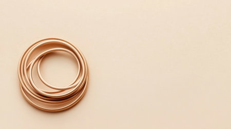 This image features a serene arrangement of circular rose gold rings on a soft pastel background, highlighting a minimalist design approach. The smooth texture and gentle colors create a balanced and elegant visual, perfect for contemporary decor and fashion applications.の素材