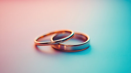 This stunning close-up photograph features two wedding rings entwined, beautifully illuminated by soft pastel lighting, capturing the essence of love and commitment.の素材
