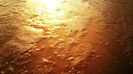 Captivating view of golden waves lapping against the shoreline, reflecting warm sunlight at sunset, evoking a serene and tranquil beach atmosphere.の素材