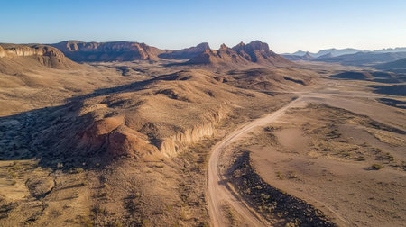 Captivating aerial view of a vast desert landscape featuring sandy terrain and striking rocky formations under clear blue skies. The scene captures the beauty of nature in a remote area, perfect for travel and adventure themes.の素材