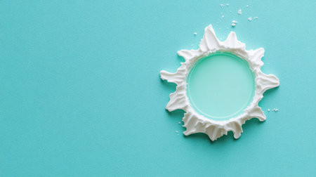 This image features a vibrant splash of white cream creating a circular pattern on a turquoise background, showcasing dynamic movement and texture.の素材
