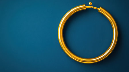 This image features a stunning gold hoop earring resting on a rich blue surface, highlighting the unique design and luxurious appeal of modern jewelry.の素材