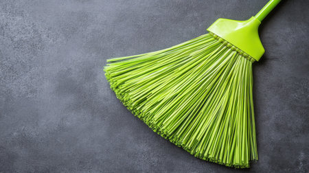 A bright green broom is placed on a gray backdrop, symbolizing cleanliness and organization. This image showcases a modern cleaning tool ideal for various household tasks.の素材