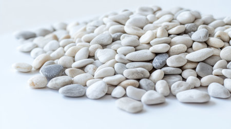 A heap of smooth white pebbles rests on a light background, ideal for decor, landscaping projects, and creating a tranquil environment.の素材