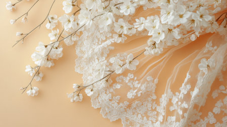 This stunning image showcases delicate white blossoms arranged beautifully with a lace fabric on a soft peach background, perfect for wedding or event styling.の素材