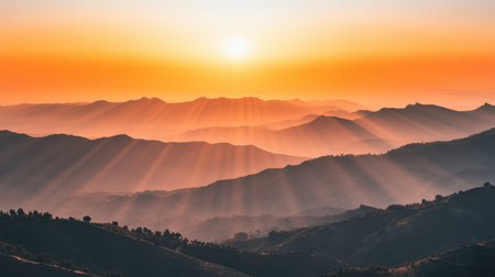 This breathtaking image captures a stunning sunrise over majestic mountain ranges, showcasing vibrant colors and beautiful rays of sunlight shining through the mist.の素材