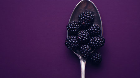 A captivating image showcasing fresh blackberries arranged on a silver spoon, set against a deep purple background that adds elegance and appeal.の素材