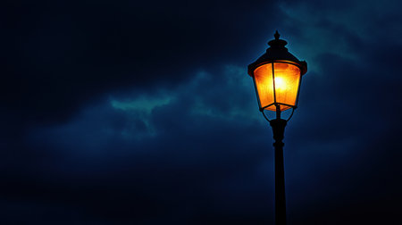 A glowing vintage lantern stands tall against a moody twilight sky, casting a warm orange light that contrasts beautifully with dark clouds.の素材