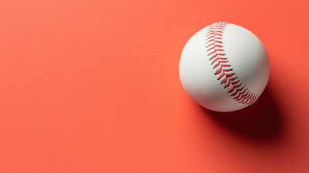 This stock photo features a white baseball resting on a bright orange background, perfect for themes related to sports, recreation, and design.の素材