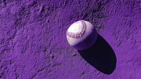 This artistic image features a purple baseball resting on a textured surface, casting a shadow that adds depth and vibrancy, ideal for sports-themed projects.の素材