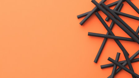 A collection of black straws scattered on a bright orange background, creating a striking visual contrast perfect for design projects and creative needs.の素材