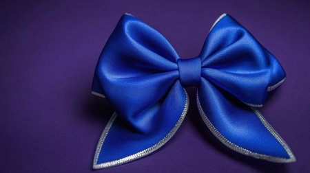This stunning blue satin bow with silver trim stands out beautifully against a deep purple background, perfect for various decorative and fashion applications.の素材