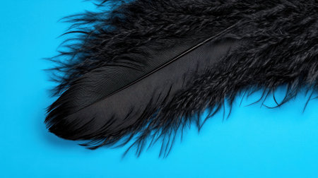 This image captures a close-up view of a black feather against a vivid blue backdrop, showcasing intricate textures and details that evoke natural beauty.の素材