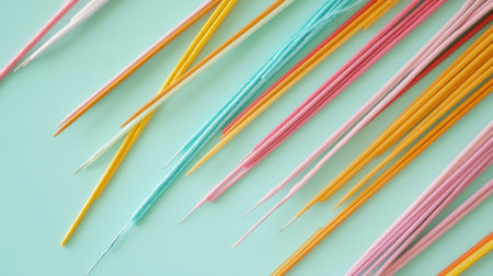 A vibrant arrangement of colorful skewers and thin sticks against a light green background, perfect for culinary uses, parties, or outdoor events.の素材