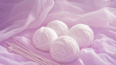 This serene image features white yarn balls and knitting needles set on soft pink fabric, perfect for illustrating crafting, creativity, and cozy leisure activities.の素材