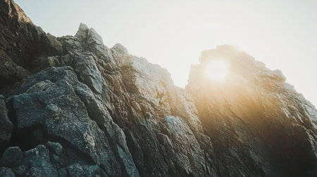 The image captures a stunning rocky cliff face illuminated by sunlight, showcasing the beauty of nature and the serene atmosphere of a coastal landscape.の素材