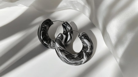 Discover the beauty of these elegant black and white marble hoop earrings, showcased on soft satin fabric, perfect for adding style to any outfit.の素材