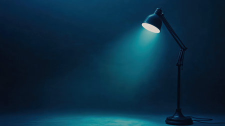A stylish desk lamp casts a soft blue light in a dark room, creating a calming atmosphere ideal for work or relaxation. Perfect for modern interiors.の素材