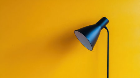 A sleek black desk lamp casts a shadow on a vibrant yellow wall, creating a minimalist and contemporary atmosphere perfect for interior design inspiration.の素材