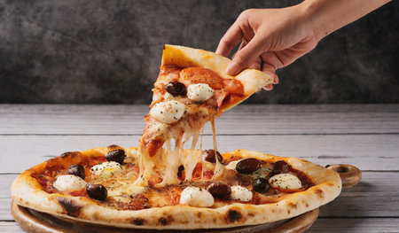 Female hand taking slice of pizza with mozzarella cheese on wooden boardの素材
