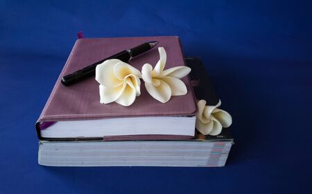 Pencil and flowers on a notebook on a blue backgroundの写真素材