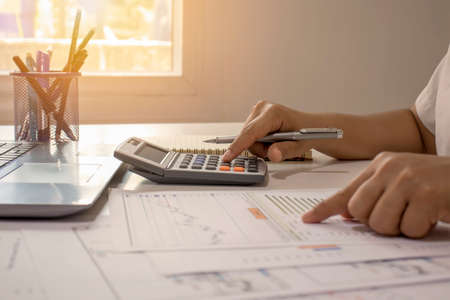 Close-up of businessmen or accountants holding a pen and pressing on the calculator to calculate business information, accounting documents, business ideas.の写真素材