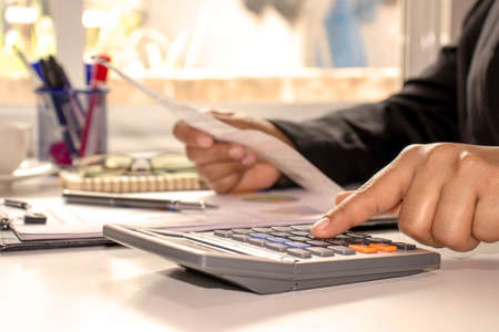 Business women who are using their fingers to press the calculator for calculating bills in the office.の写真素材